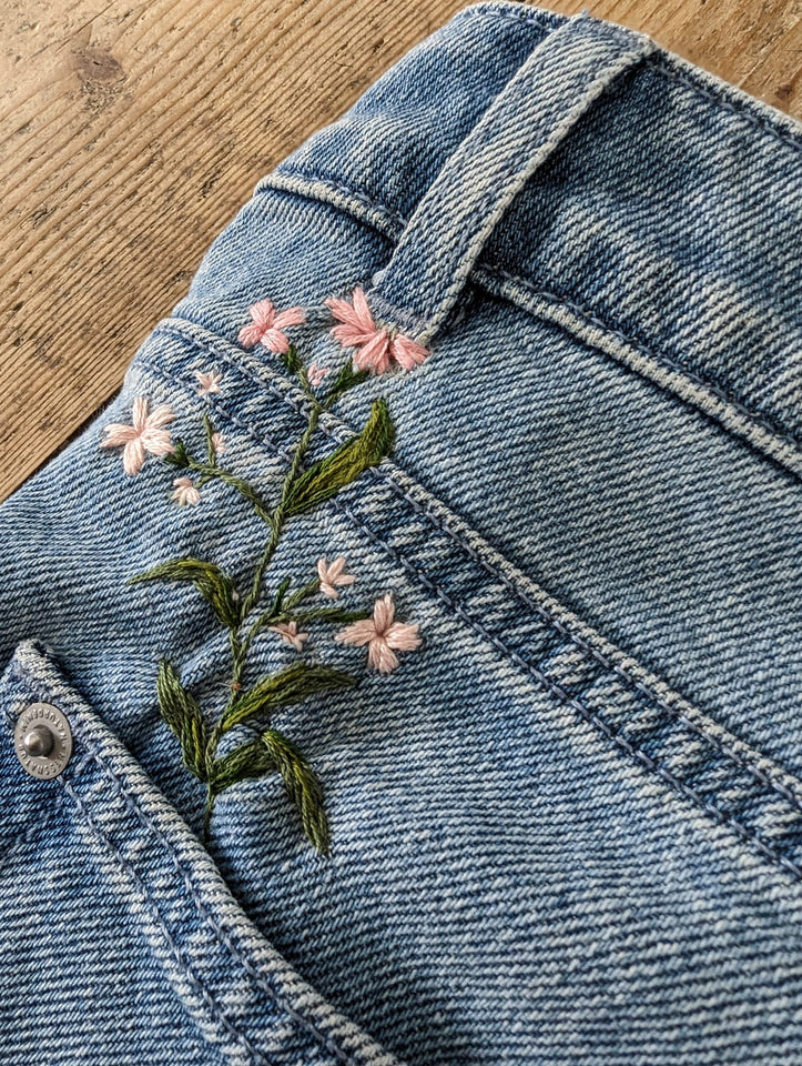 Eine Jeans, die durch eine gestickte Rosa Blume repariert wurde